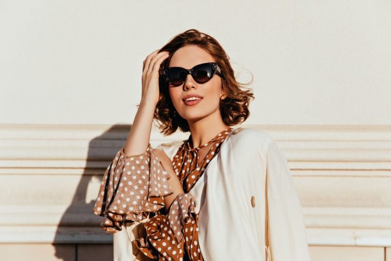Lovely woman in vintage outfit expressing interest. Outdoor shot of glamorous happy girl in sunglasses