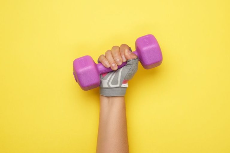 female hand in a pink sports glove holds a purple one kilogram d